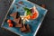 Snack from shrimps and red caviar with black bread, decorated with physalis and greens on plate over black background.Healthy food