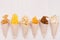 Snacks collection in craft paper cornets on white wooden board, top view, border.