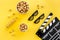 Snacks for film watching. Popcorn and soda near clapperboard, glasses on yellow background top view