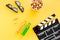 Snacks for film watching. Popcorn and soda near clapperboard, glasses on yellow background top view