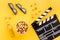 Snacks for film watching. Popcorn and soda near clapperboard, glasses on yellow background top view