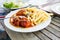 Snacks to beer on a white plate. Bavarian fried sausages, fried potatoes, chips on a wooden table background.