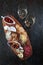 Snacks for wine. Cheese and cold cuts with nuts on a wooden Board. Textured aged dark background. The view from the top. Copy of