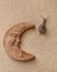 A snail crawls on a salmon pink wall next to a funny terracotta crescent moon drawn with a human face