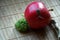 Snail sitting on red apple and tree trunk and go to green broccoli, wooden bamboo backdrop, close-up animal background