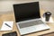 Snapped view of a desk with an open laptop, a notepad, a glass of coffee, and a cell phone ready to work from home. Technology