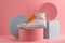 Sneaker on pink background with colorful cylinders and cube