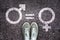 Sneaker shoes on asphalt background with gender symbols, gender equality concept