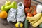 Sneakers ,oranges, tomatoes, Apple, pear ,lemon, sports bracelet, tomato juice ,bananas, milk, fruits and vegetables on a brown