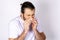 Sneezing guy into a napkin on a white background. Runny nose symptoms of coronavirus. Allergic rhinitis