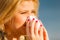 Sneezing woman into handkerchief, outside sunny shot