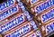 Snickers bars in wrappers lined up on an angle in rows, flat lay format.