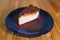 Snickers cheesecake on a blue saucer on a large bright wooden table