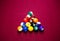 Snooker multicolored balls lay as a pyramid on the table. Closeup view. Billiard red table with cue and balls. Leisure, hobby,