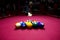 Snooker multicolored balls lay as a pyramid on the table. Closeup view. Billiard red table with cue and balls. Leisure, hobby,