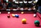 Snooker multicolored balls lay as a pyramid on the table. Closeup view. Billiard red table with cue and balls. Leisure, hobby,