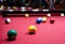 Snooker multicolored balls lay on the table. Closeup view. Billiard red table with cue and balls. Leisure, hobby,