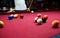 Snooker multicolored balls lay on the table. Closeup view. Billiard red table with cue and balls. Leisure, hobby,