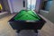 Snooker Pool Billiards green table with complete set of balls and two pool cues in a modern games room