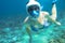 Snorkeling girl in bikini and full-face snorkeling mask in coral reef. Snorkel in coral reef of tropical sea.