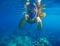 Snorkeling woman underwater showing thumbs. Snorkel in full face mask.