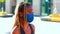 A snotty afro girl stands on the street wearing a mask during the coronavirus.