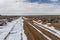 Snow along empty dirt road cutting through open high desert in rural New Mexico