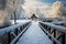 Snow blankets a wooden bridge, transforming it into a winter scene