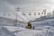 Snow cannon and ski lifts on sunlit mountain slope