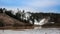 Snow cannons spray snow on slalom hill without snow.