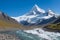 A snow-capped mountain peak reaching towards a clear blue sky generated by Ai