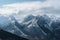 snow-capped mountain range, with clouds gathering in the distance