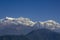 A snow-capped mountain range under a blue sky with white clouds and green forest on the slopes. annapurna circuit