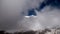 A snow capped mountain top pokes through the clouds and mist in the high alps in France.