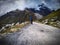 Snow capped mountains and rough road journey. Tourism exploration of new areas. Person pointing at top.