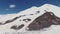Snow-capped peak of Mount Elbrus with gentle slopes with ski runs and tourists