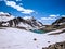 Snow clad mountains with a small lake and white clouds in blue sky background