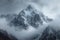 Snow cloaked mountain stands tall beneath a moody, overcast sky