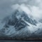 Snow cloaked mountain stands tall beneath a moody, overcast sky