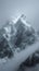 Snow cloaked mountain stands tall beneath a moody, overcast sky