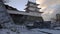 Snow covered Akashi Castle and modern tower on early winter morning