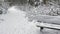 A snow covered bench at a hiking trail