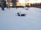 Snow-covered benches in park on winter evening