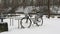 A snow-covered bicycle strapped to a bicycle rack. Difficult winter weather conditions make cycling impossible. Snowfall