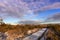 Snow covered boardwalk leading to a lighthouse under wispy clouds. Fire Island, New York.