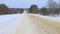 Snow-covered country road. Fairytale forest on the horizon