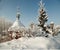 Snow covered dome with cross of orthodox chapel under hoary fir tree