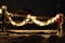 Snow covered evergreen garland draped on a country fence with lights at night