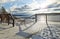 Snow-covered fence and descent to the beach on the winter embankment in the morning