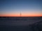 Snow-covered field along the road at sunset on a clear frosty winter evening